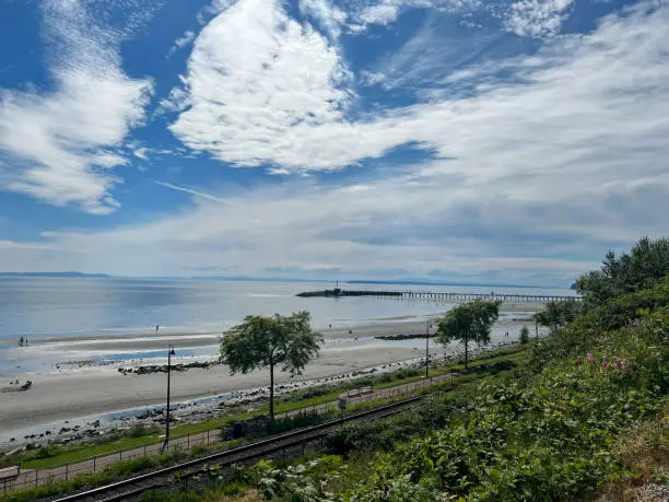 White Rock, British-Columbia, Canada, view on the pier, trees, railroad track, beach, ocean, and sky, low tide, summer day
