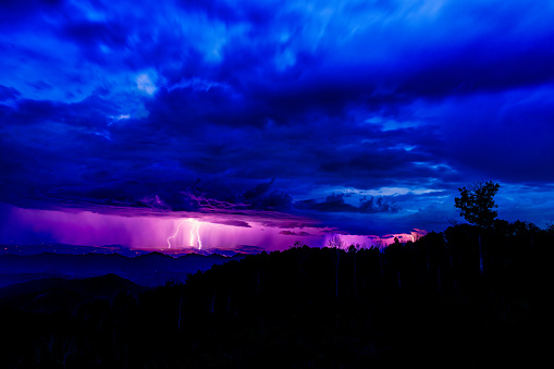 Twilight Lightning Strike During Severe Storm - Electrical storm scenic landscape above mountains and valley with dramatic steel blue clouds.