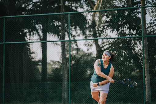 Asian Chinese female tennis player Serving The Ball practicing at tennis court