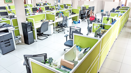 High angle view and selective focus of an office interior with bright color cubicles and dark wheeled chairs at lunch time-break