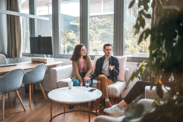 istock Casually Dressed Married Couple Holding Hands on  Couch 1588602037