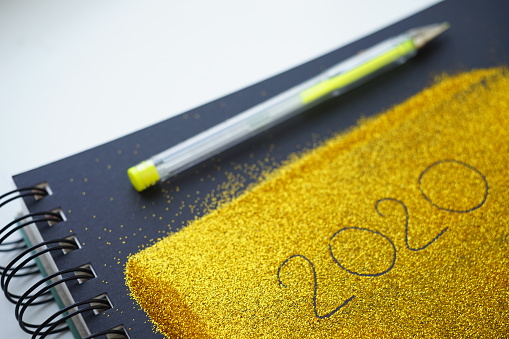 Golden notebook with 2020 inscription, gel pen for new year idea