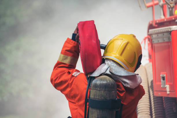Firefighter Rescue training in fire fighting extinguisher. Firefighter fighting with flame using fire hose chemical water foam spray engine. Fireman wear hard hat, safety suit uniform for protection formación de bomberos de rescate en extintores contra incendios. bombero luchando con llamas usando manguera contra incendios químico de espuma de agua pulverizadora motor. bombero usa casco, uniforme de traje de seguridad para protección