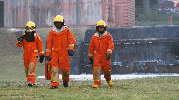 istock Firefighter Rescue team training in fire fighting extinguisher. Firefighter teamwork fighting with flame using fire hose chemical water foam spray engine. Fireman wear hard hat, safety suit uniform 1588675431