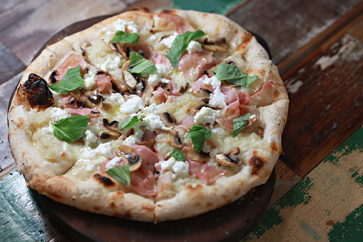 A freshly baked Pizza Patata topped with Buffalo Mozzarella, potato, mushrooms, cooked ham, extra virgin olive oil and basil.