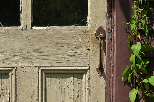 Old door with peeling paint, rusty handle, and copy space in the middle