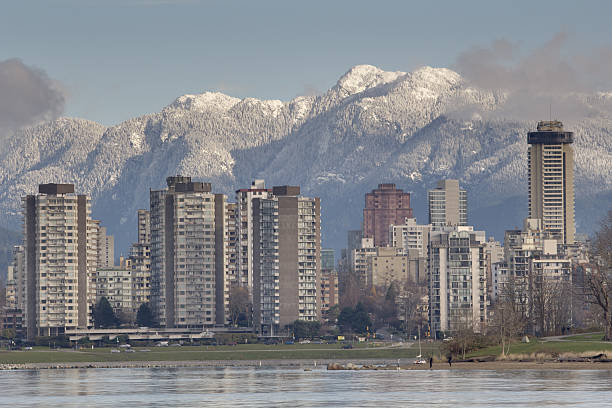 Vancouver West End Skyline The view across English Bay, the apartments and condominiums of the West End, and the snow capped North Shore Mountains in Vancouver, British Columbia, Canada. beach english bay vancouver skyline stock pictures, royalty-free photos & images