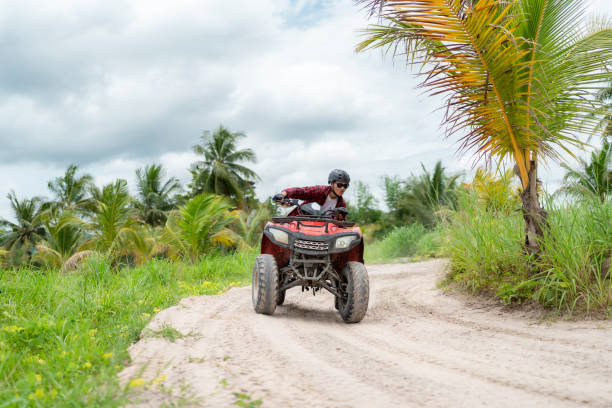 istock Asian guy having fun while driving an atv in the jungle alone. coconut tree background 1588791090