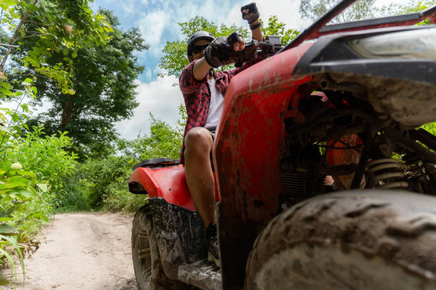 istock Asian guy having fun while driving an atv in the jungle alone. Raised hands, smiling and happy. 1588794687