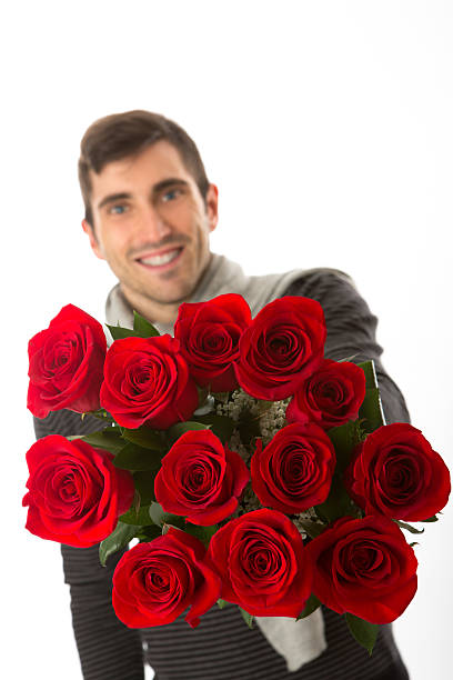 istock young handsome man with red roses 158879623