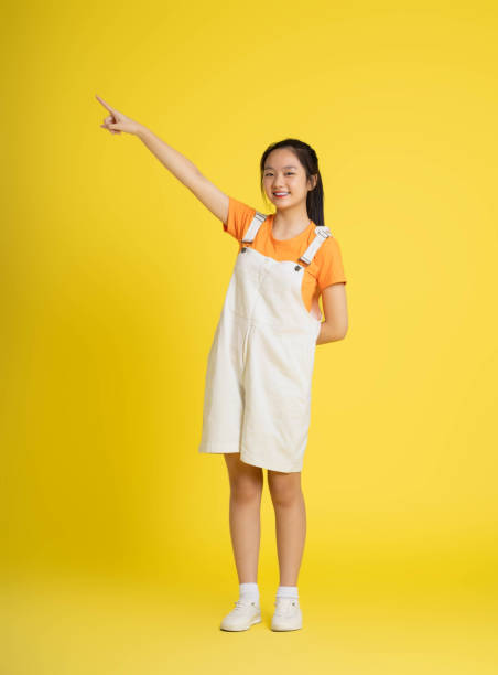 istock cute asian girl posing on a yellow background 1588855797