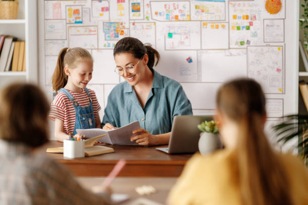 Happy kids and teacher at school Happy kids and teacher at school. Woman and children are talking in the class. elementary school stock pictures, royalty-free photos & images