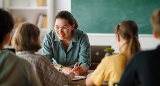 Happy kids and teacher at school Happy kids and teacher at school. Woman and children are talking in the class. teachers stock pictures, royalty-free photos & images