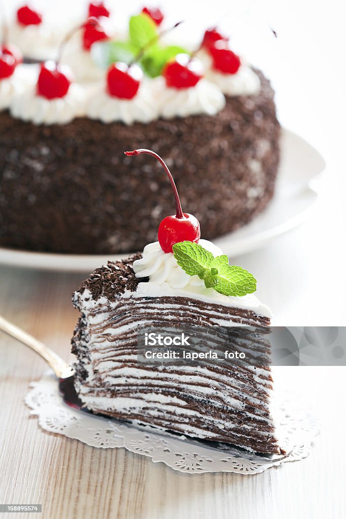 Piece of chocolate crepe cake Piece of chocolate crepe cake with whipped cream and glazed cherries, selective focus Baked Pastry Item Stock Photo