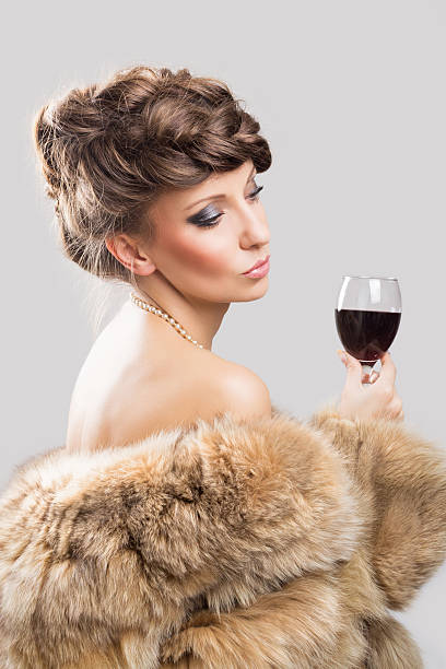 Elegante bella donna con cappotto di pelliccia marrone e bere vino - foto stock