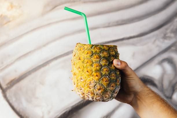istock Man holding a delicious pineapple filled with a cocktail with a straw 1588961184