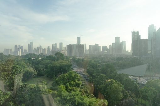 Jakarta skyscraper commercial district buildings landscape view in hazy early morning hour with huge garden area Indonesia