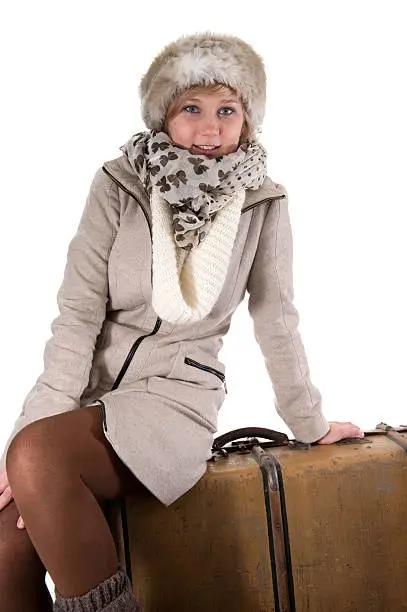 young woman in winterclothes with suitcases, isolated on white background