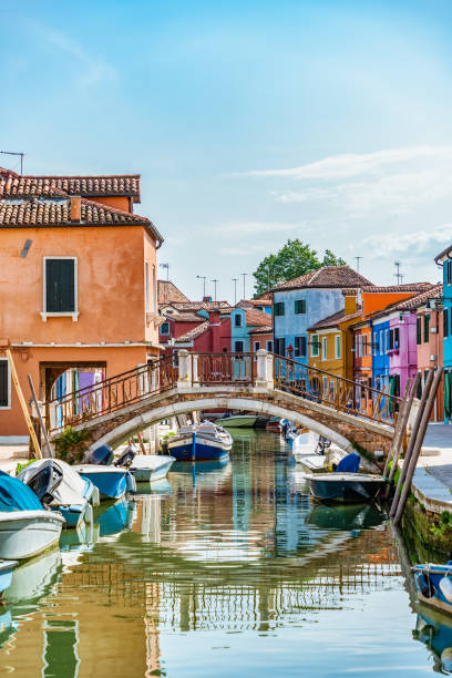 pittoresca scena idilliaca colorata con una barca attraccata sui canali d'acqua a burano venezia italia. - photography urban scene venice italy veneto foto e immagini stock