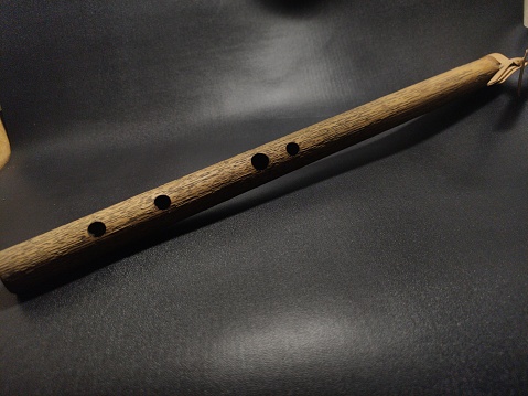 Traditional flute from West Java made of brown bamboo, 20 cm in size with 4 holes, usually played to achieve high notes, black background