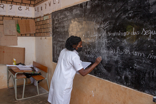 Manica, Mozambique - February 02, 2023: Teacher writing in a blackboard during an elementary class