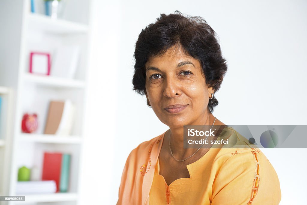 Mature Indian woman Portrait of a 50s Indian mature woman smiling, isolated on white background Culture of India Stock Photo