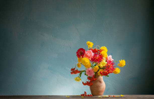 istock red and yellow flowers on jug in sunlight on background dark wall 1589057723