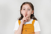 little girl putting finger up to lips & ask silence on white background