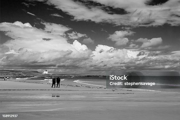 Photo libre de droit de Couple Marchant Sur La Plage De Bamburgh banque d'images et plus d'images libres de droit de Bamburgh - Bamburgh, Bâtiment vu de l'extérieur, Ciel