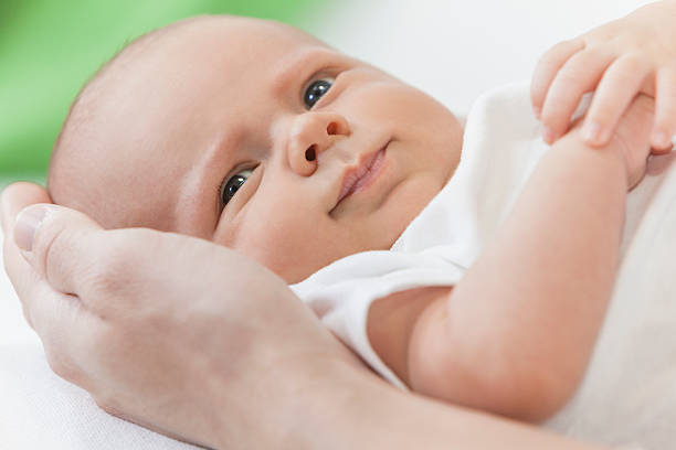 istock Father Holding Young Smiling Baby Hands 158913963