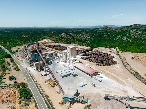 Aerial view of a mining quarry with heavy machinery, surrounded by forest.