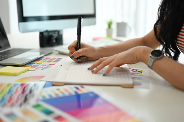 istock Young creative woman working with color palette, choosing color samples for design project at graphic studio. 1589155169