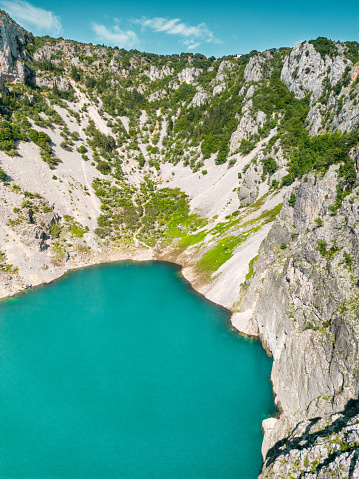 Scenic aerial view of Imotski Blue Lake (Modro jezero) in limestone crater, Dalmatia, Croatia. Nature summer landscape, popular tourist attraction, outdoor travel background.