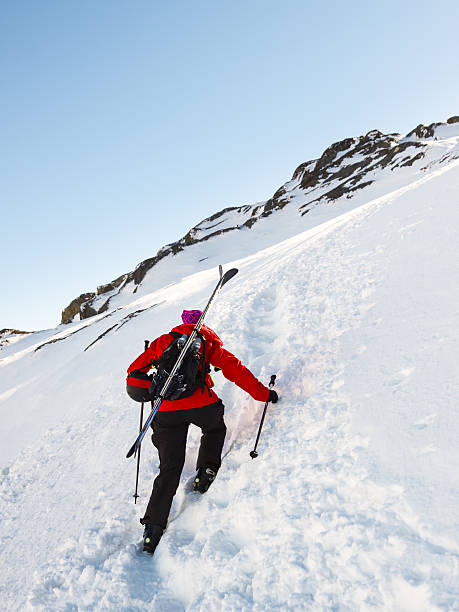 Woman skier with skis on backpack stock photo