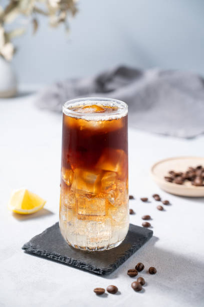istock Coffee with tonic in a tall glass with ice and lemon on a light blue background with coffee beans and fruit. Trendy summer craft refreshing drink. 1589176662