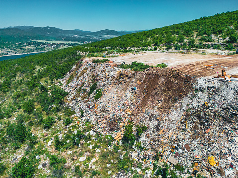 Illegal dumping of waste in nature, wild garbage dumping site. Open landfill with piles of garbage polluting the environment. Aerial view.