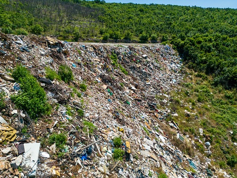 Illegal dumping of waste in nature, wild garbage dumping site. Open landfill with piles of garbage polluting the environment. Aerial view.