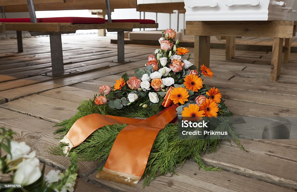 Orange and white flower wreath laid next to a white casket A funeral and floral arrangements Bouquet Stock Photo