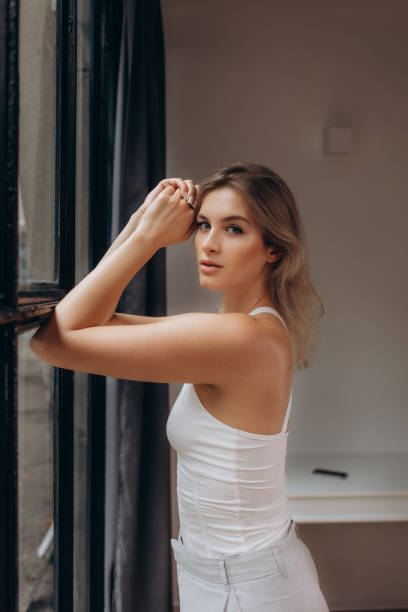istock beautiful blonde standing by the window 1589209824