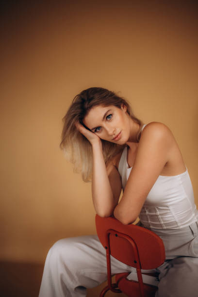 istock blonde with blue eyes dressed in white on an orange background 1589209834