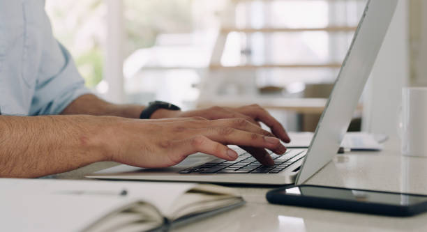 istock Hands, man and laptop keyboard at table for planning, online research and working on internet. Closeup, computer and typing on technology for website connection, email and digital copywriting at desk 1589226218