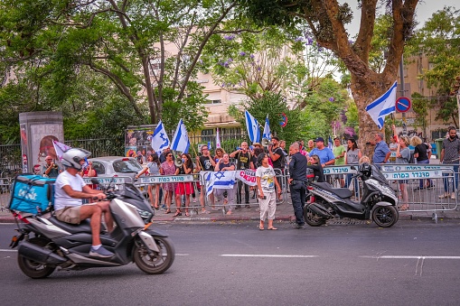 Tel Aviv, Israel – June 01, 2023: A small group of left-wing protesters stands on the side of the road in Tel Aviv, while police officer is guarding them.