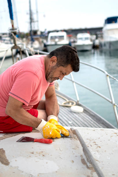 istock Worker repairing with spatula to boat 1589235163