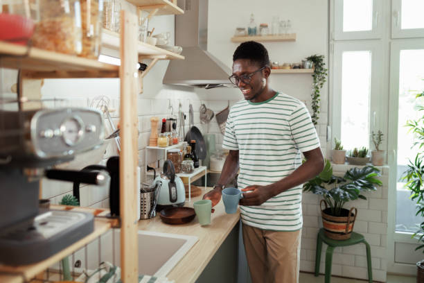 istock Young smiling man making coffee in a domestic kitchen 1589237757