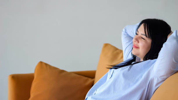 istock Black-haired woman enjoys relaxing on sofa with smile 1589249524