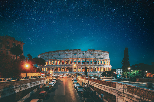 Rome, Italy. Bold Bright Blue Azure Night Starry Sky With Glowing Stars Above Colosseum Also Known As Flavian Amphitheatre In Evening Or Night Time. Travel To Italy.