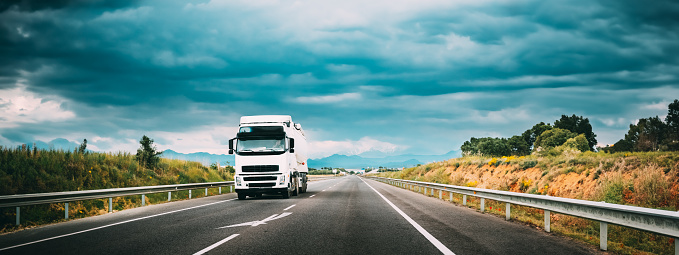 White Truck Or Traction Unit In Motion On Road, Freeway. Asphalt Motorway Highway Against Background Of Mountains Landscape. Business Transportation And Trucking Industry.