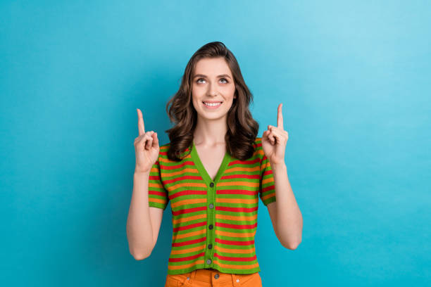 istock Photo of young optimistic charming lady brown curls pointing fingers empty space looking interested news isolated on blue color background 1589257937