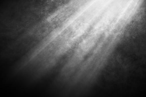 White and gray smoke against black background with light beams