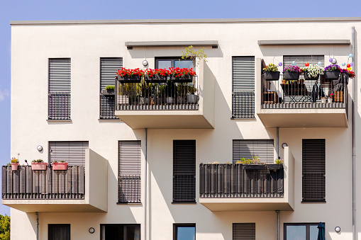 Balcony of Modern Apartment Building. Modern Sunny Balconies with Flowers, Sun Protection Blinds Windows of Multistory Apartments. Exterior Design Facade High-rise Building.